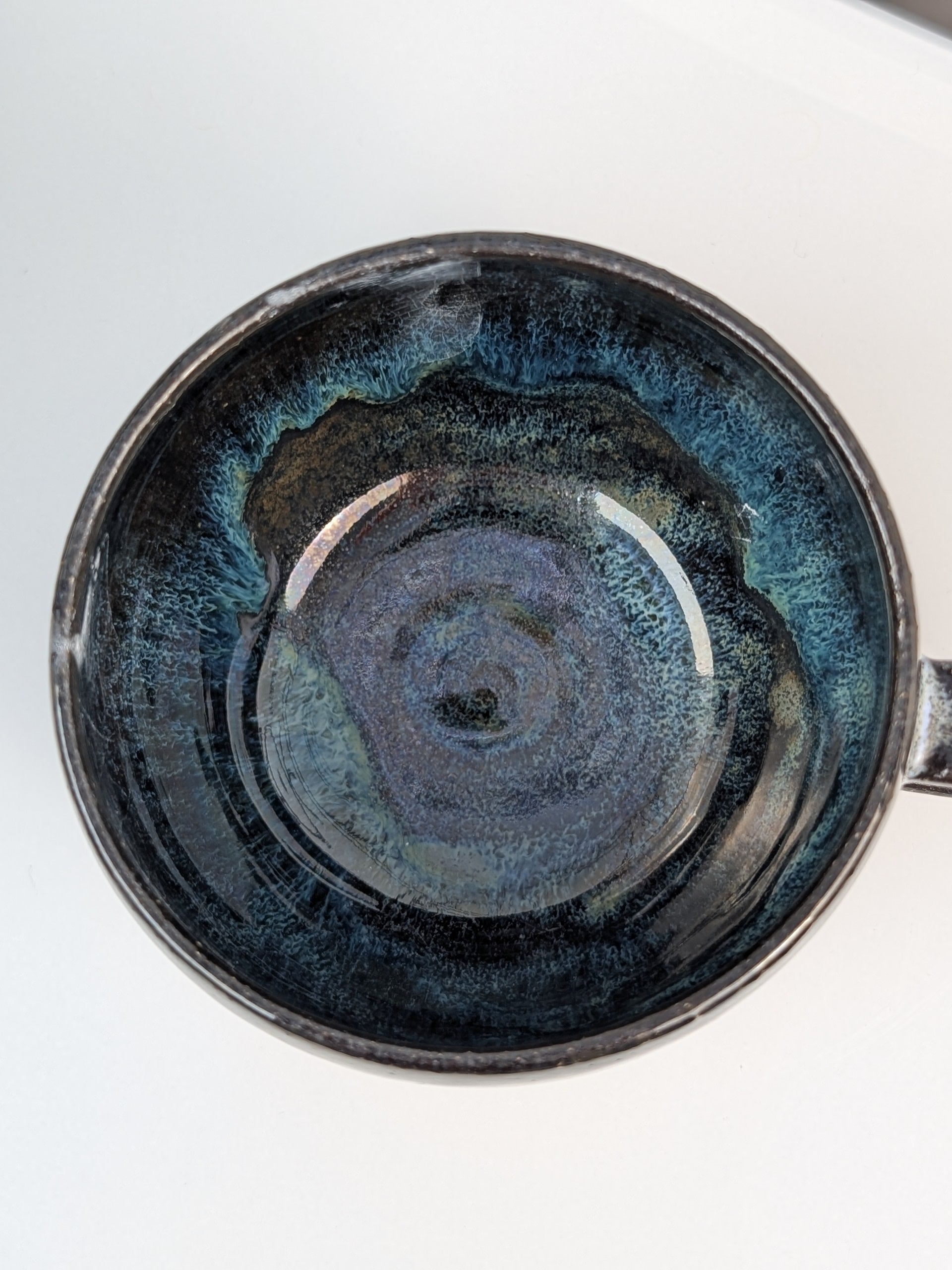 Handmade black, white, and blue glazed ceramic cup, top view