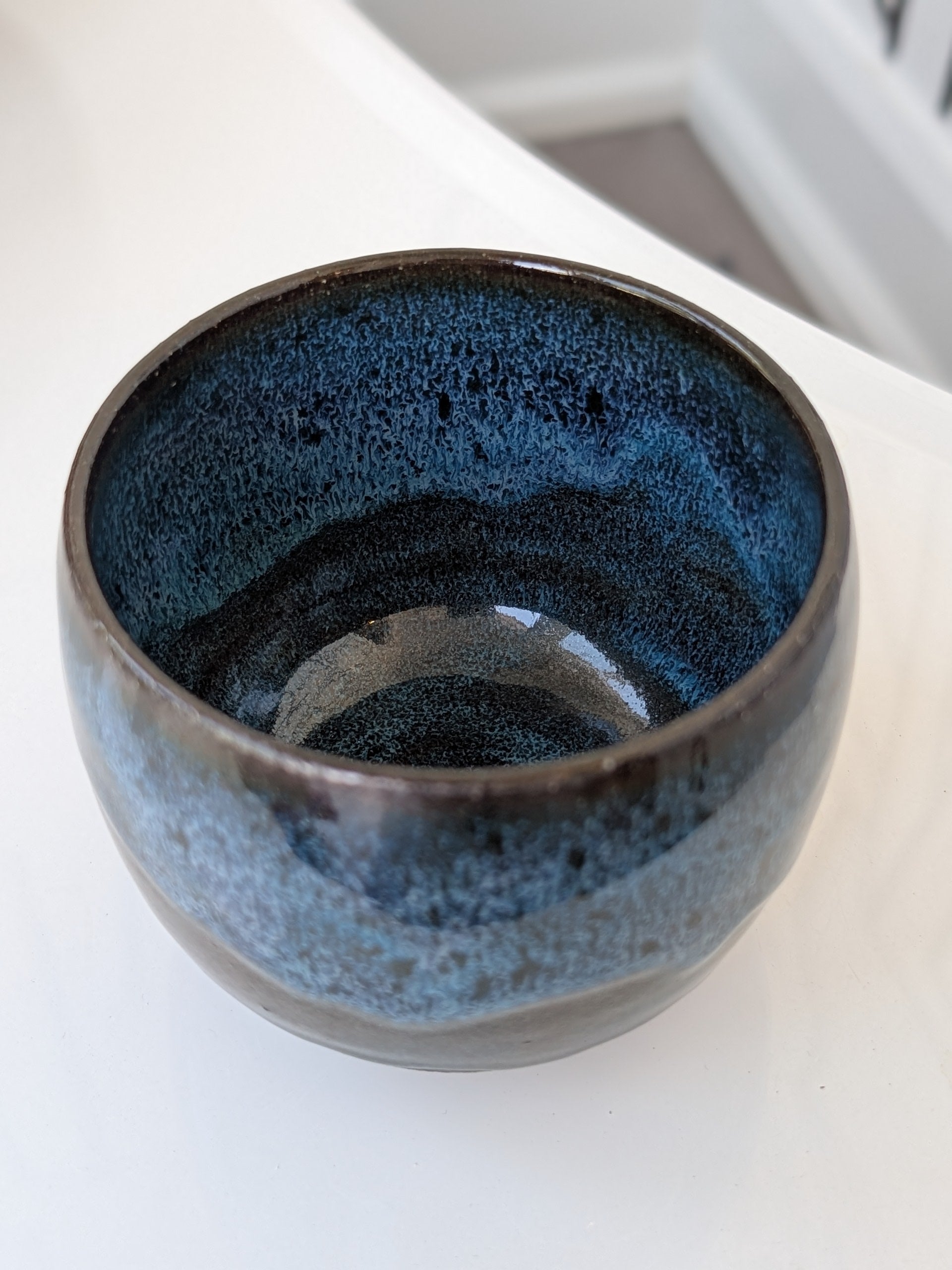 Ceramic bowl with blue speckled interior on a white surface