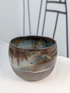 Handmade brown, white, and blue glazed ceramic cup, front view