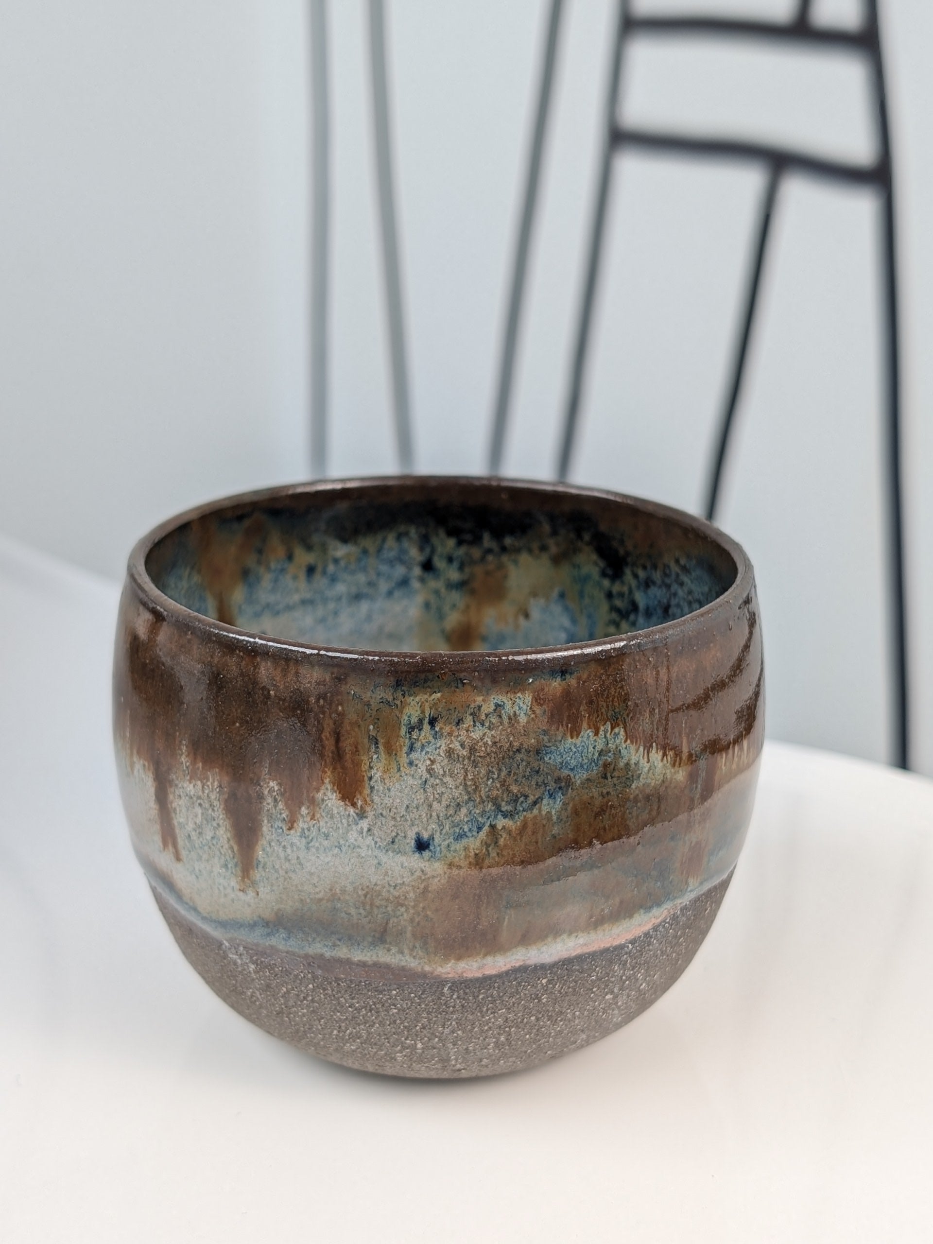 Handmade brown, white, and blue glazed ceramic cup, front view