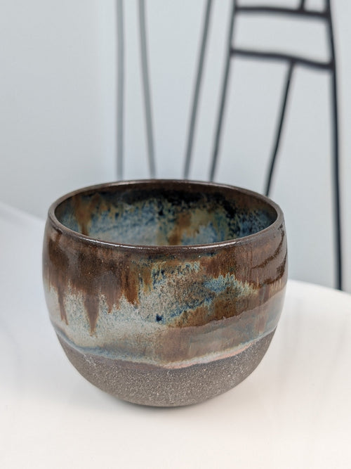 Handmade brown, white, and blue glazed ceramic cup, front view