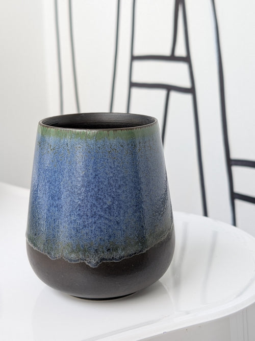 Ceramic cup with blue and black glaze on a white surface