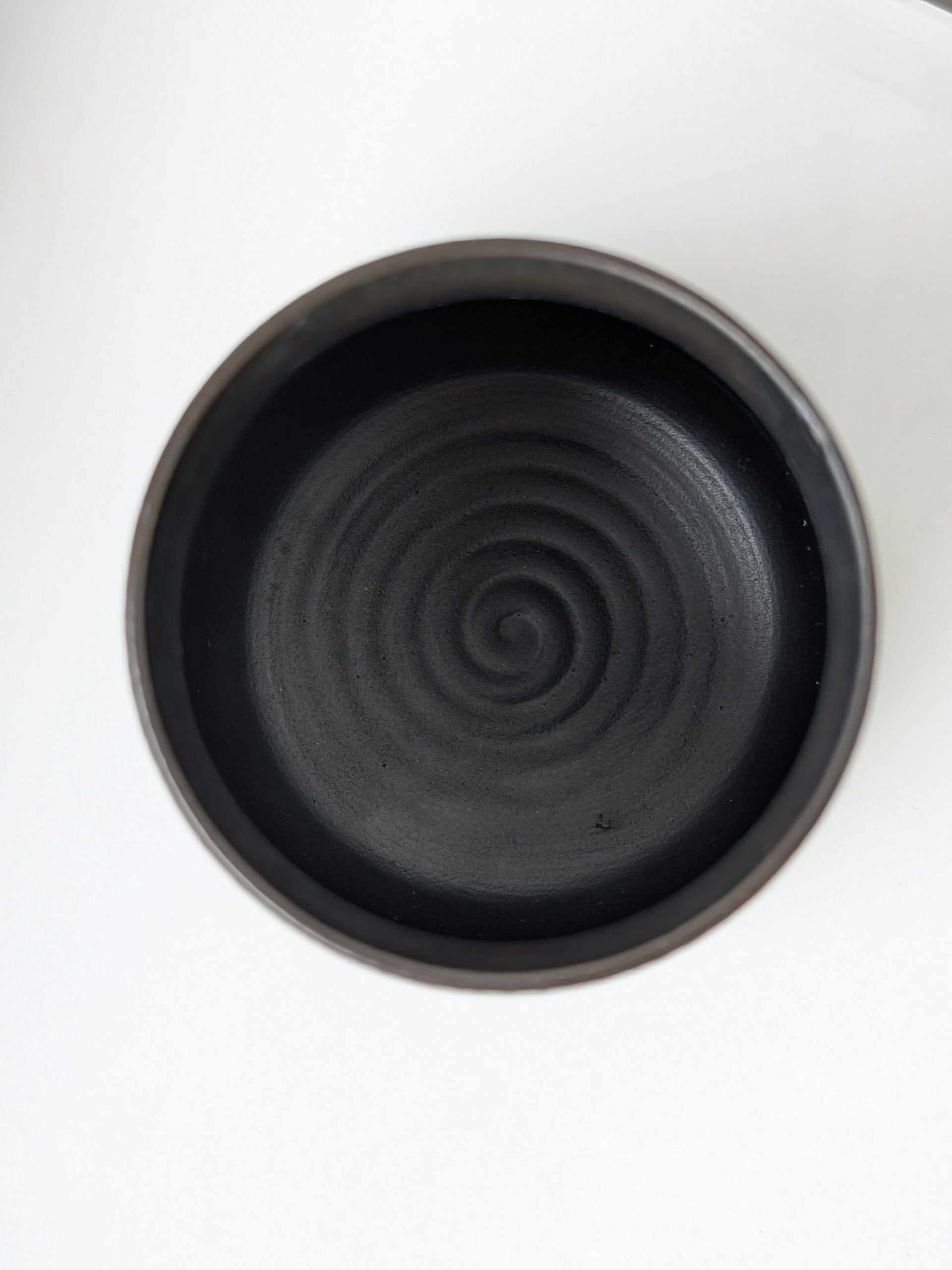 Black ceramic dish with spiral pattern on a white background