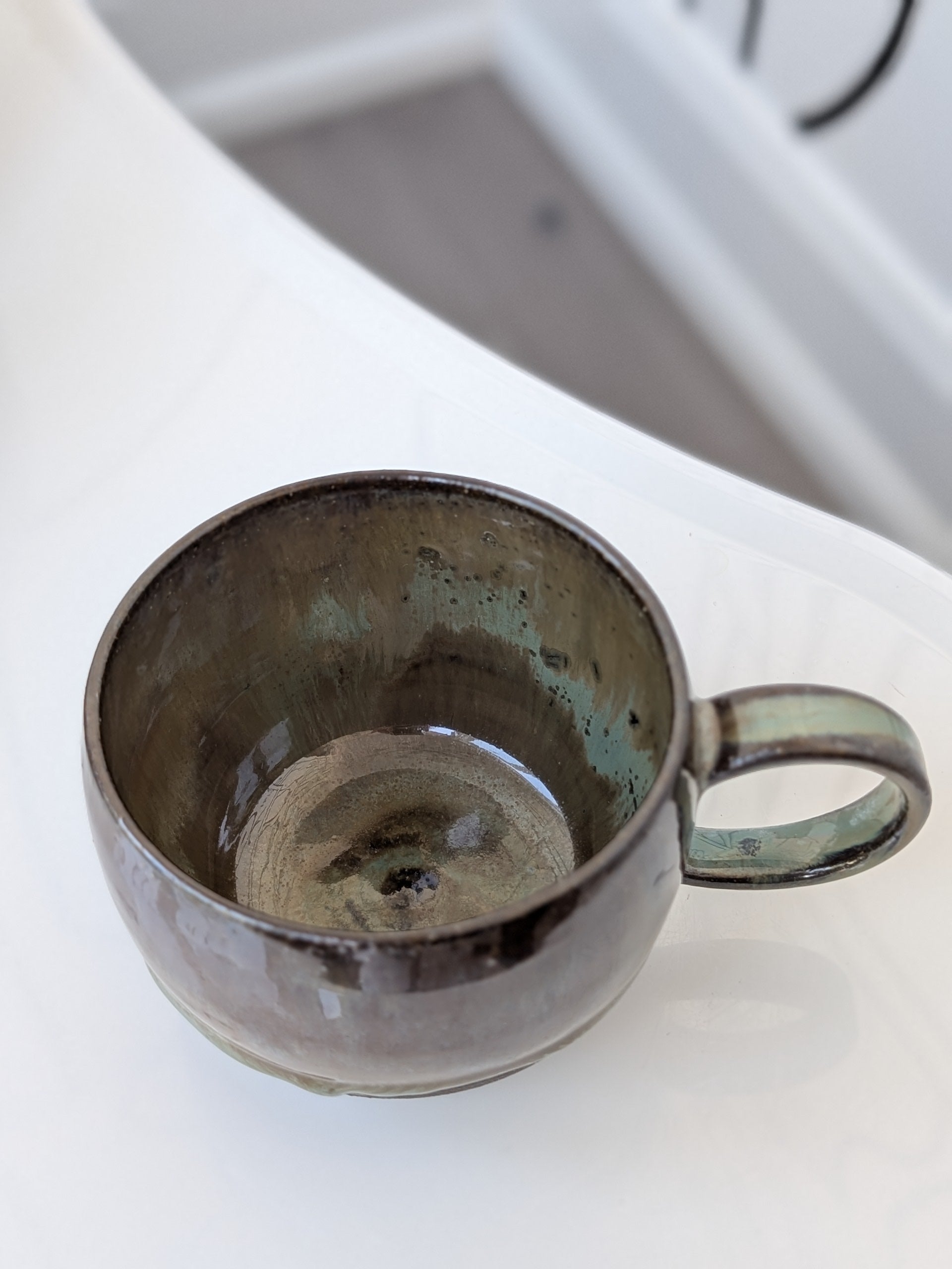 Handmade brown and green glazed ceramic cup, isometric view