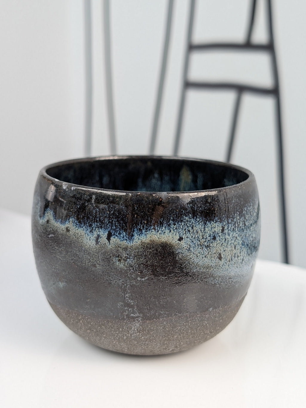 Handmade black, white, and blue glazed ceramic cup, front view