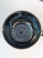 Handmade black, white, and blue glazed ceramic cup, top view