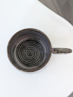 Ceramic mug with a spiral design on a white surface