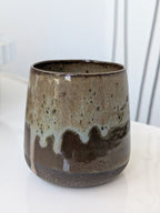 Ceramic mug with brown and beige glaze on a white surface