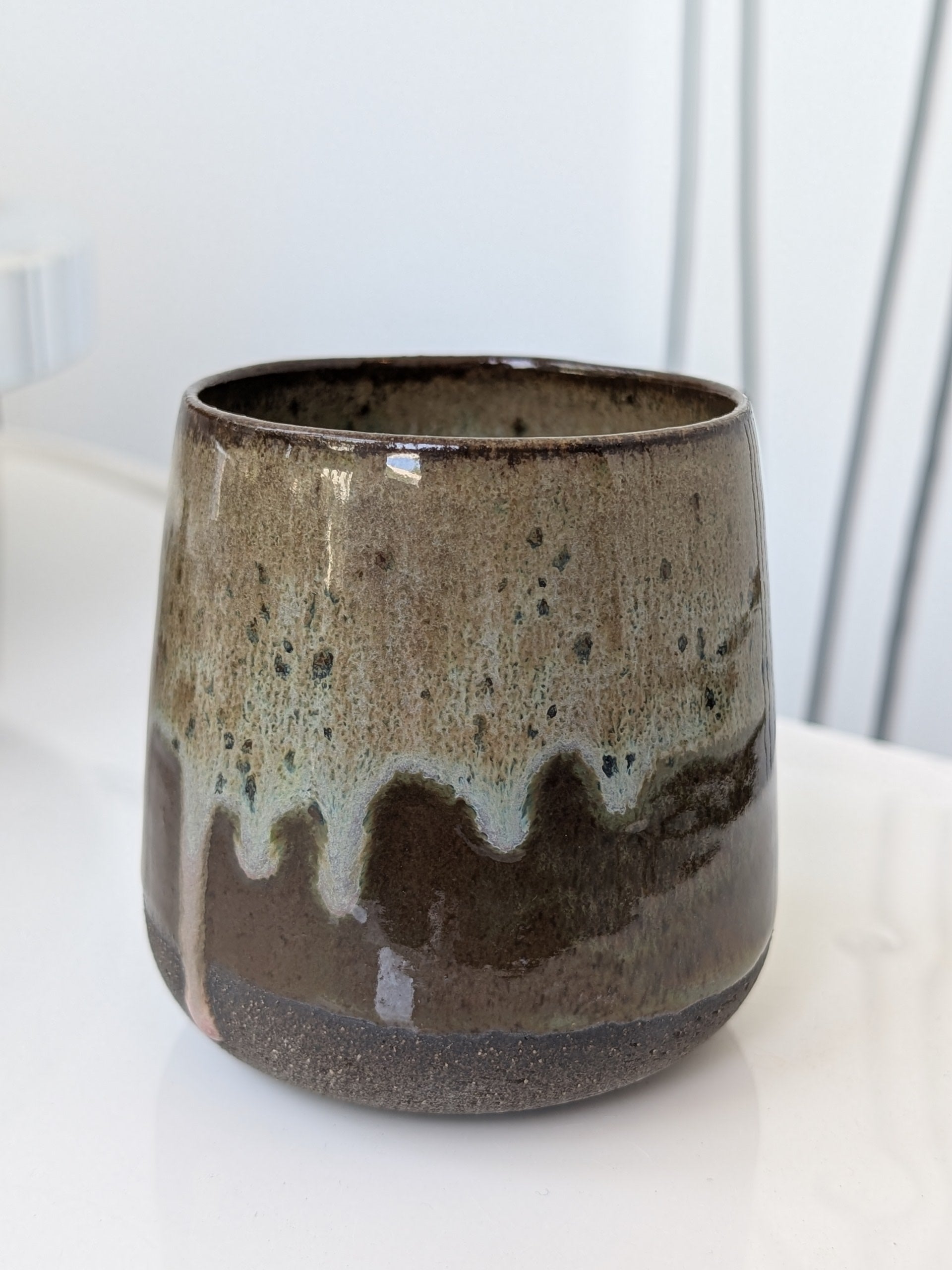 Ceramic mug with brown and beige glaze on a white surface