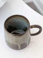 Handmade ceramic mug with a textured surface on a white background
