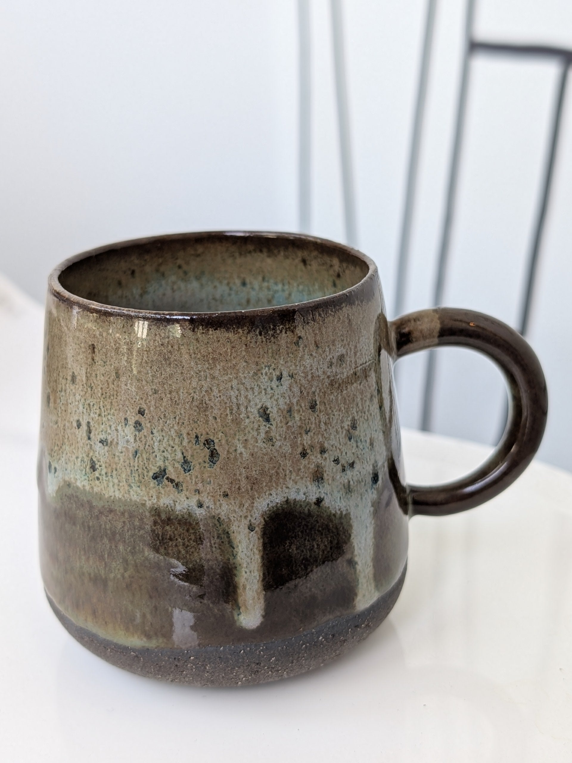 Brown ceramic mug with speckled texture on a white surface