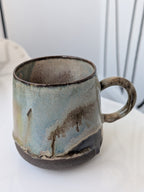Handmade ceramic mug with a textured surface on a white background
