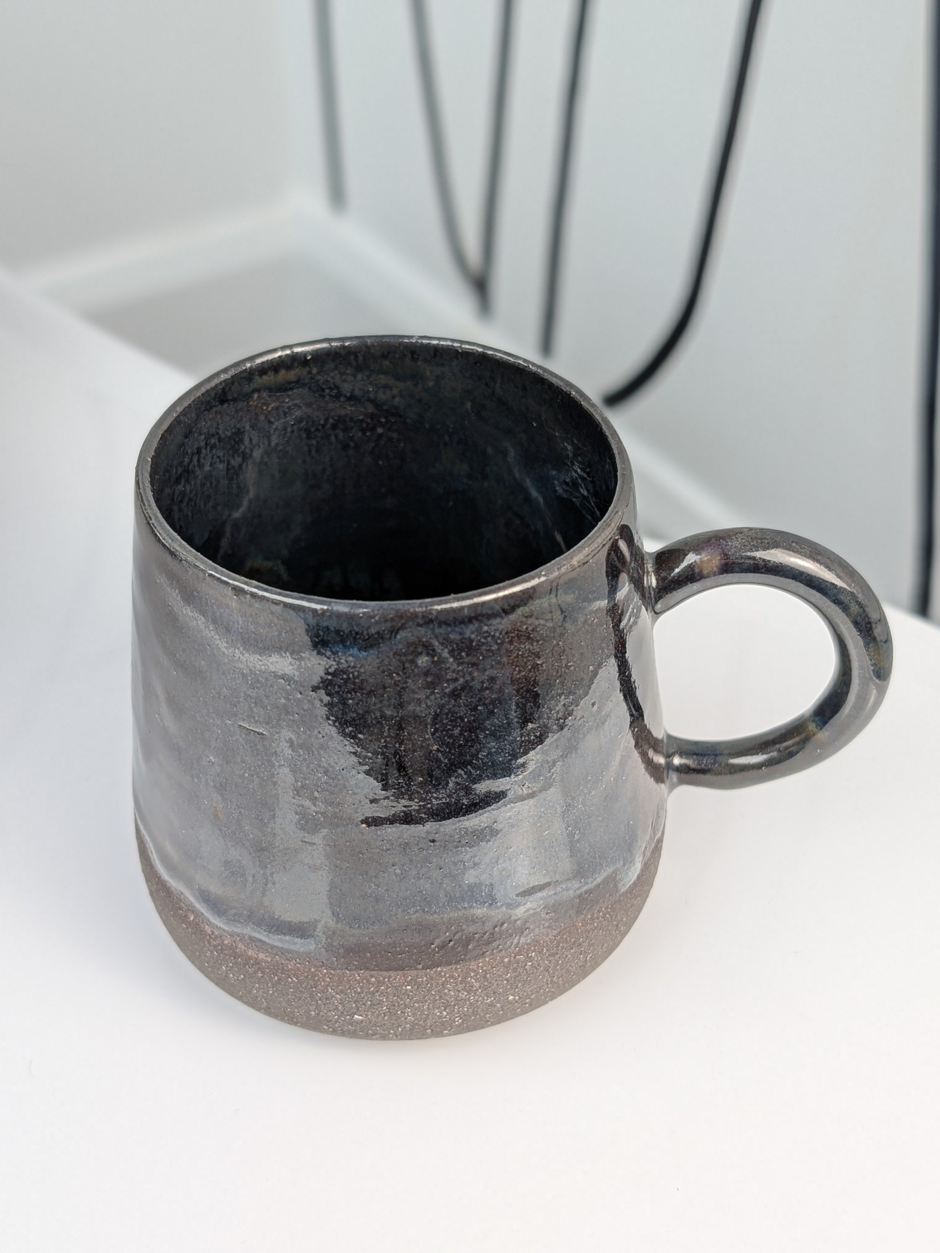 Handmade black glazed ceramic cup, isometric view