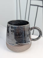 Handmade black glazed ceramic cup, side view with handle