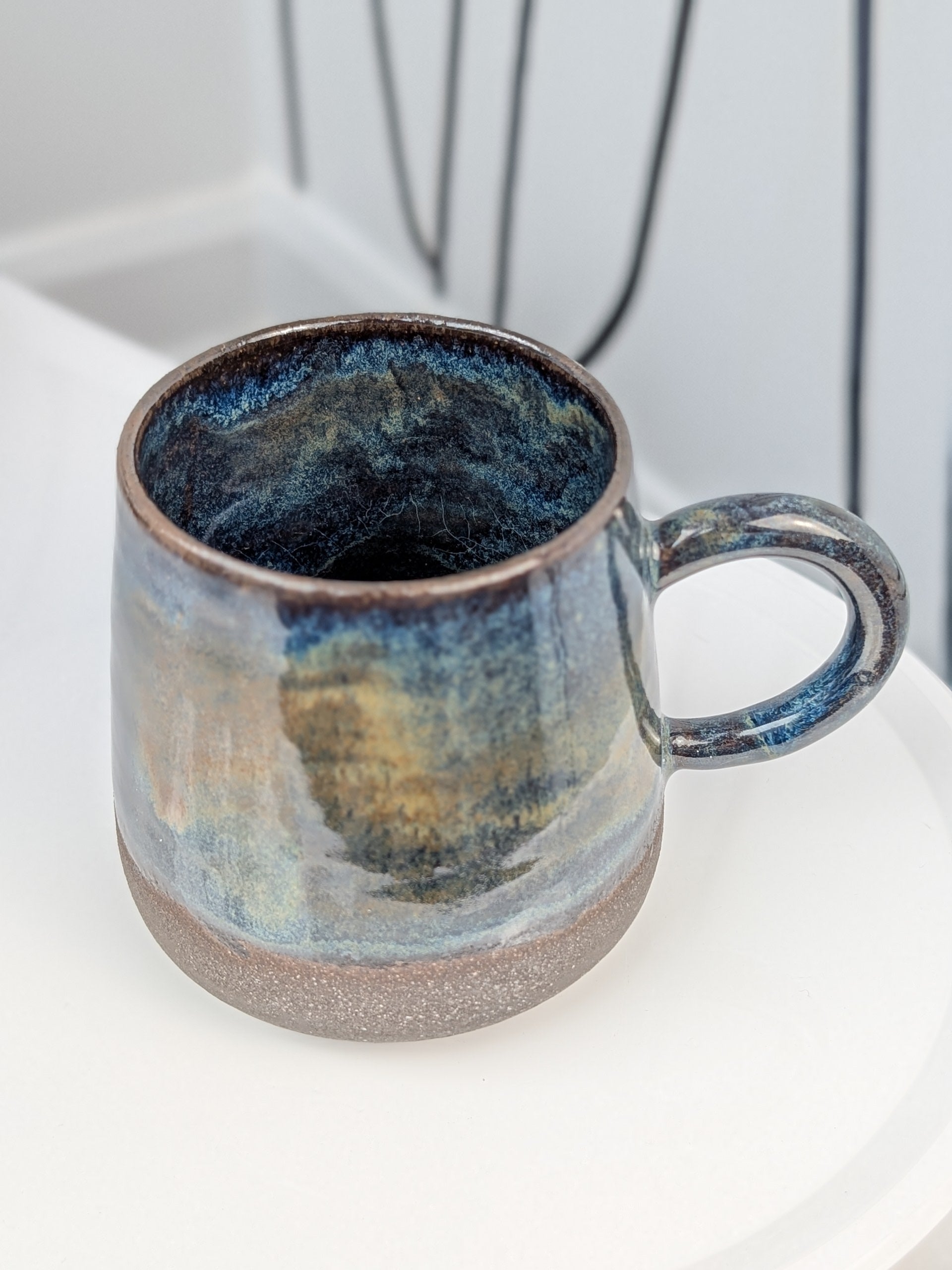 Handmade blue and brown glazed ceramic cup, isometric view