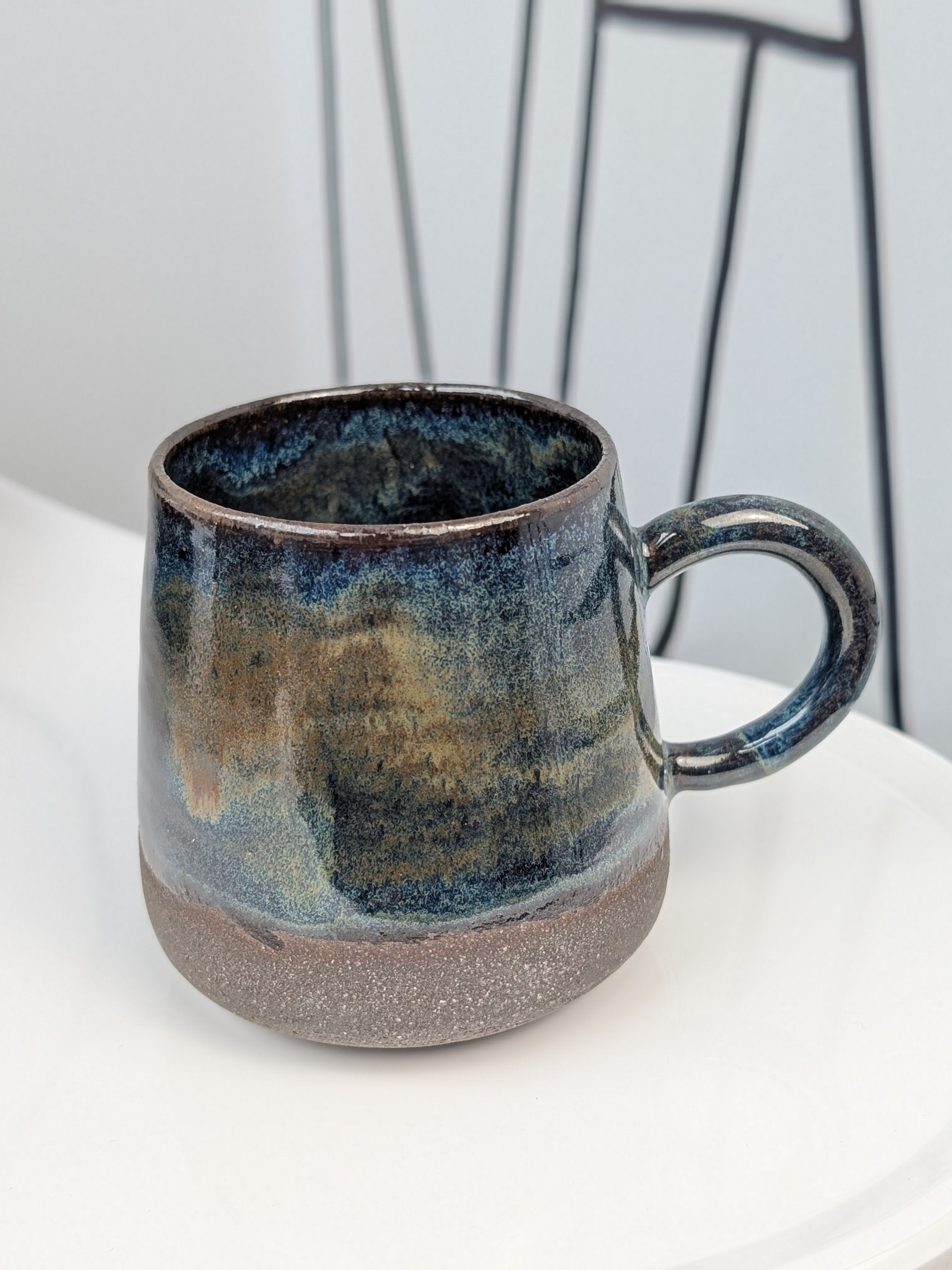 Handmade blue and brown glazed ceramic cup, side view with handle