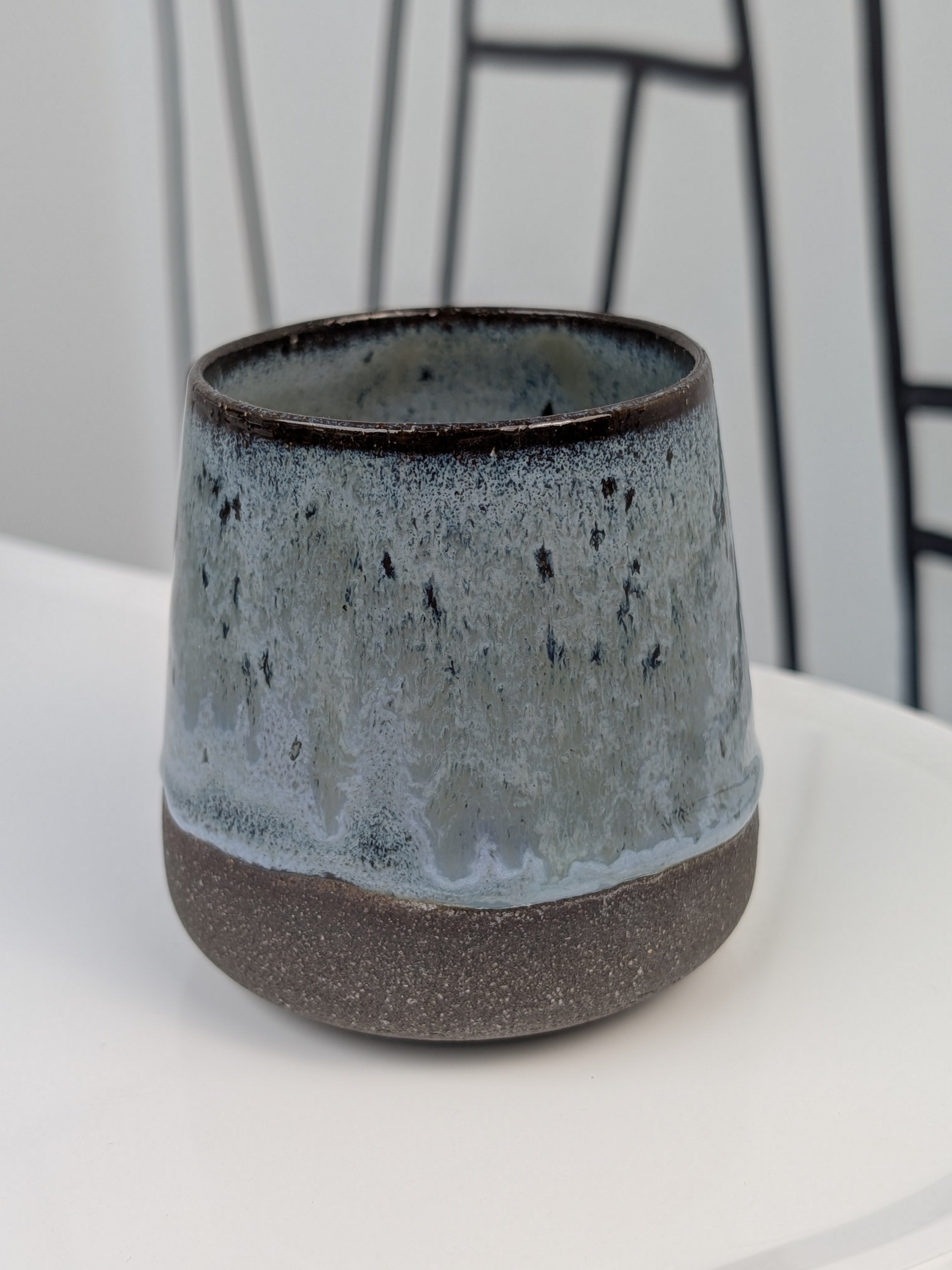 Handmade blue and black glazed ceramic cup, front view