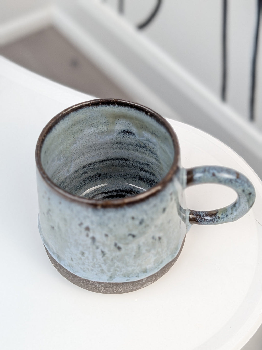 Handmade blue and black glazed ceramic cup, isometric view