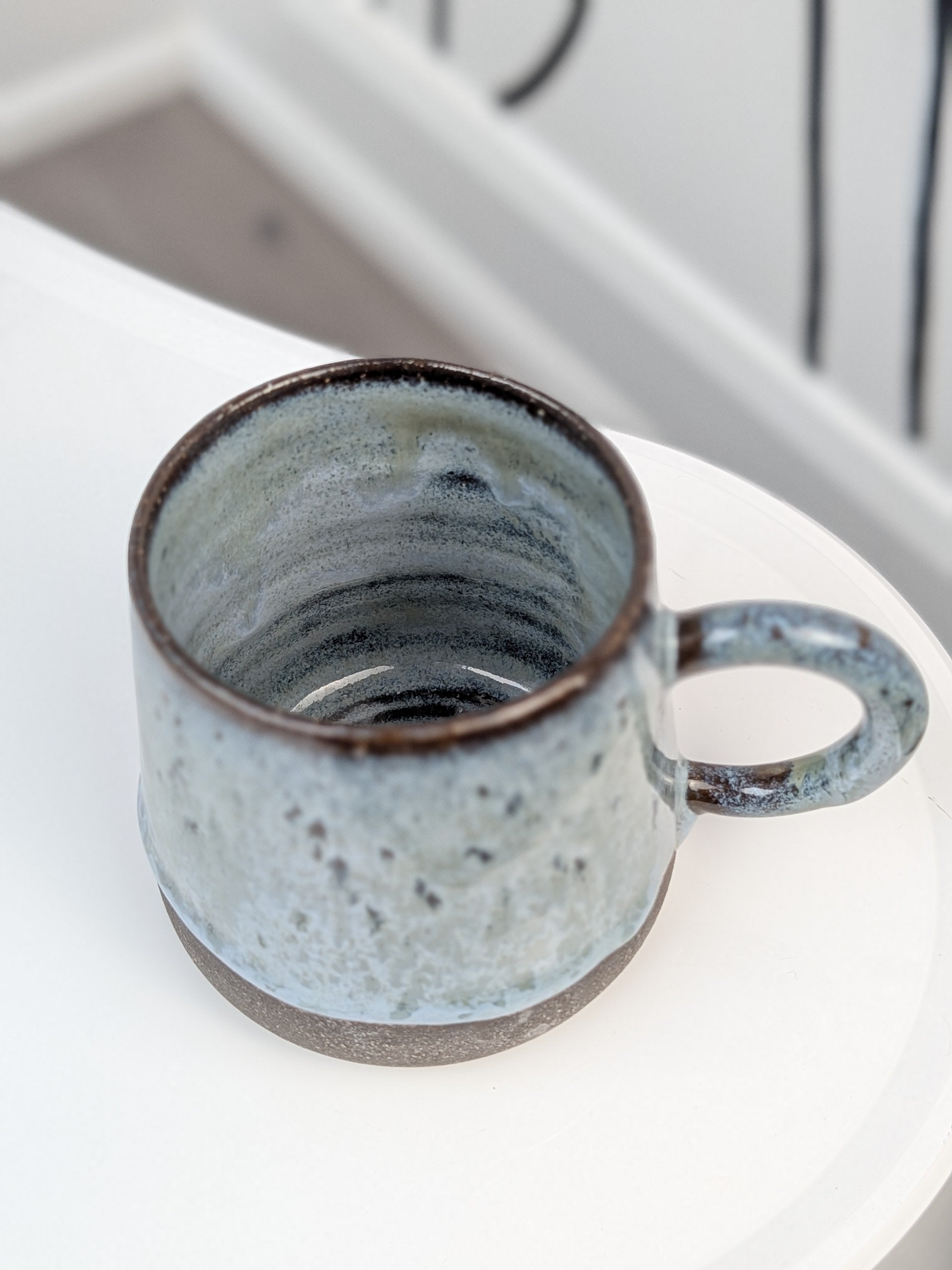 Handmade blue and black glazed ceramic cup, isometric view