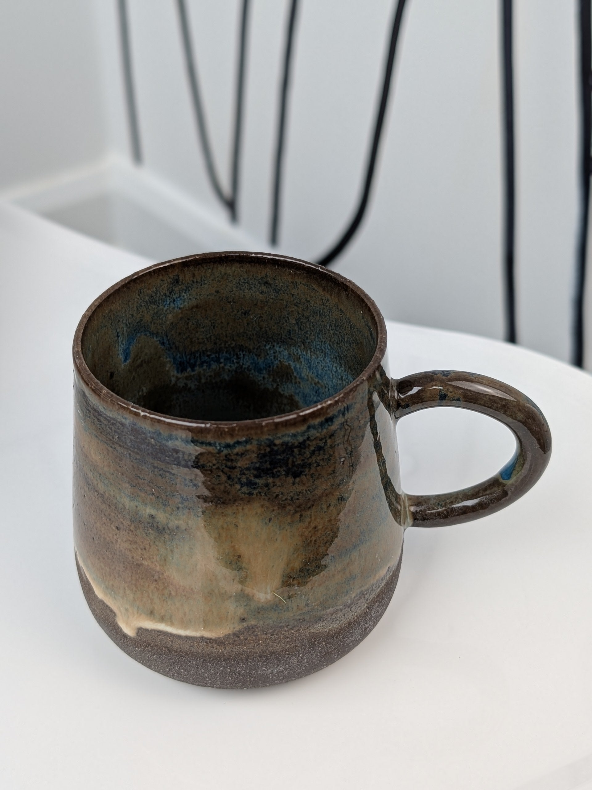 Handmade blue and brown glazed ceramic cup, isometric view