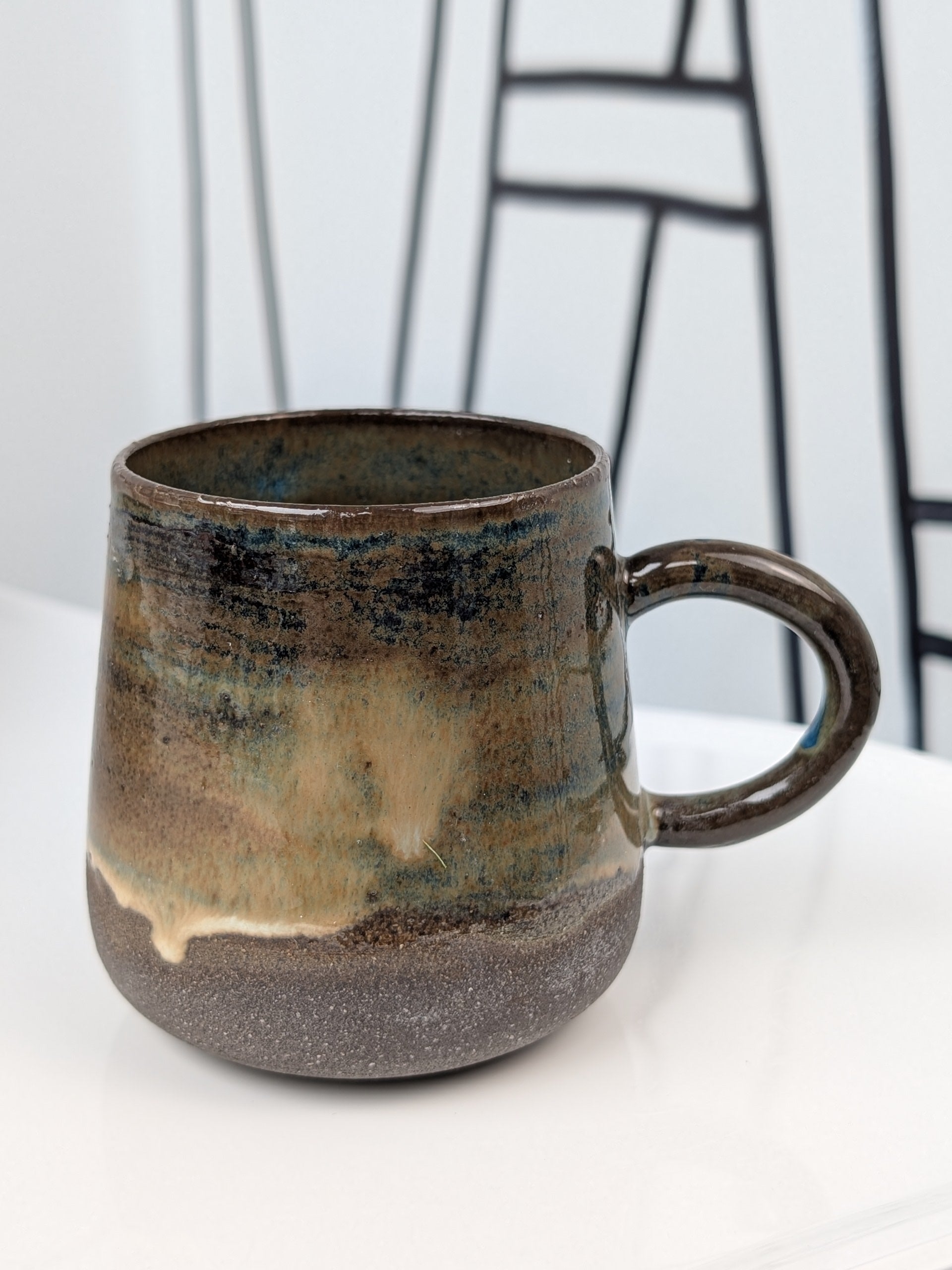 Handmade blue and brown glazed ceramic cup, side view with handle