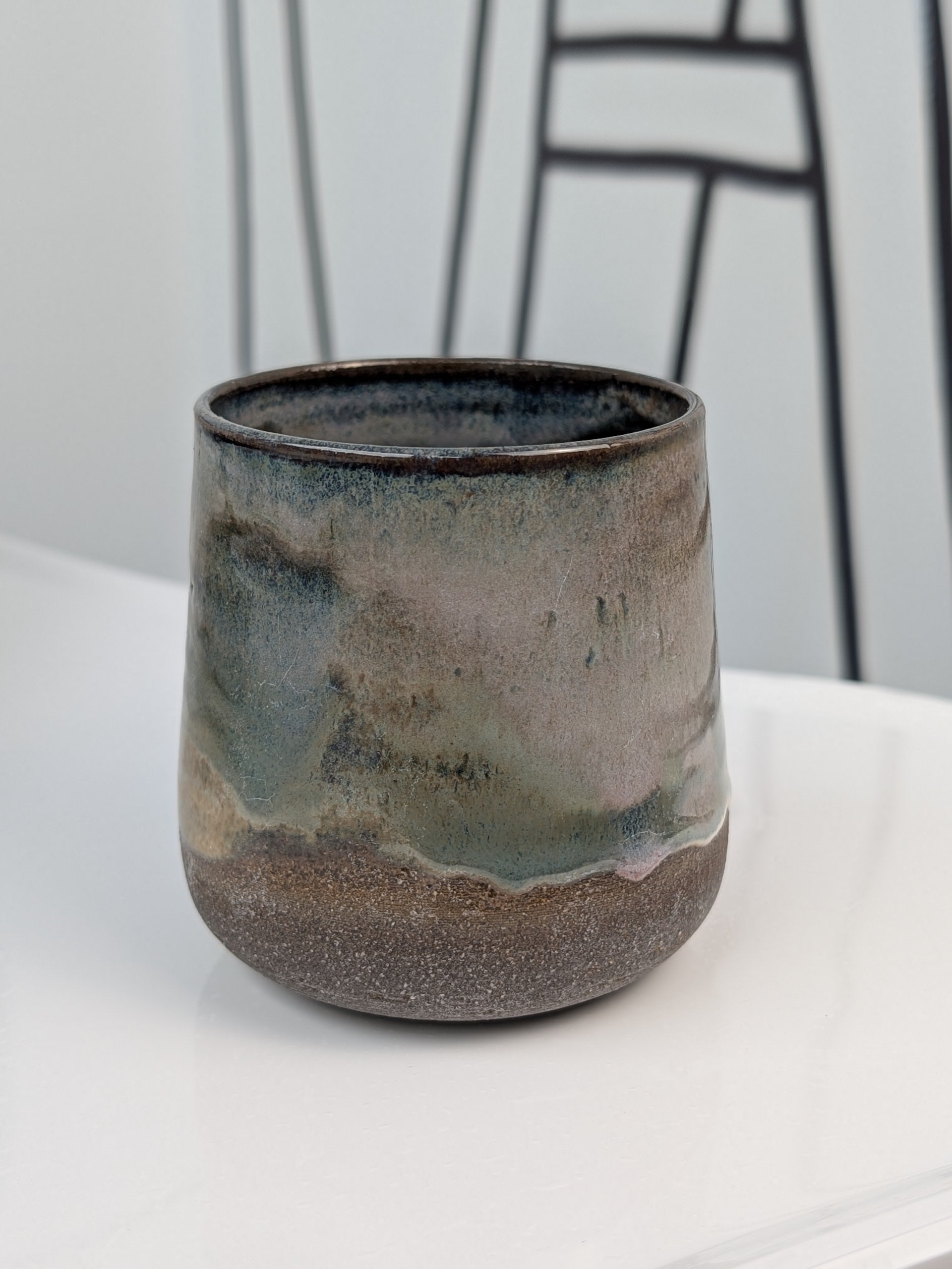 Handmade brown, green, and pink glazed ceramic cup, front view