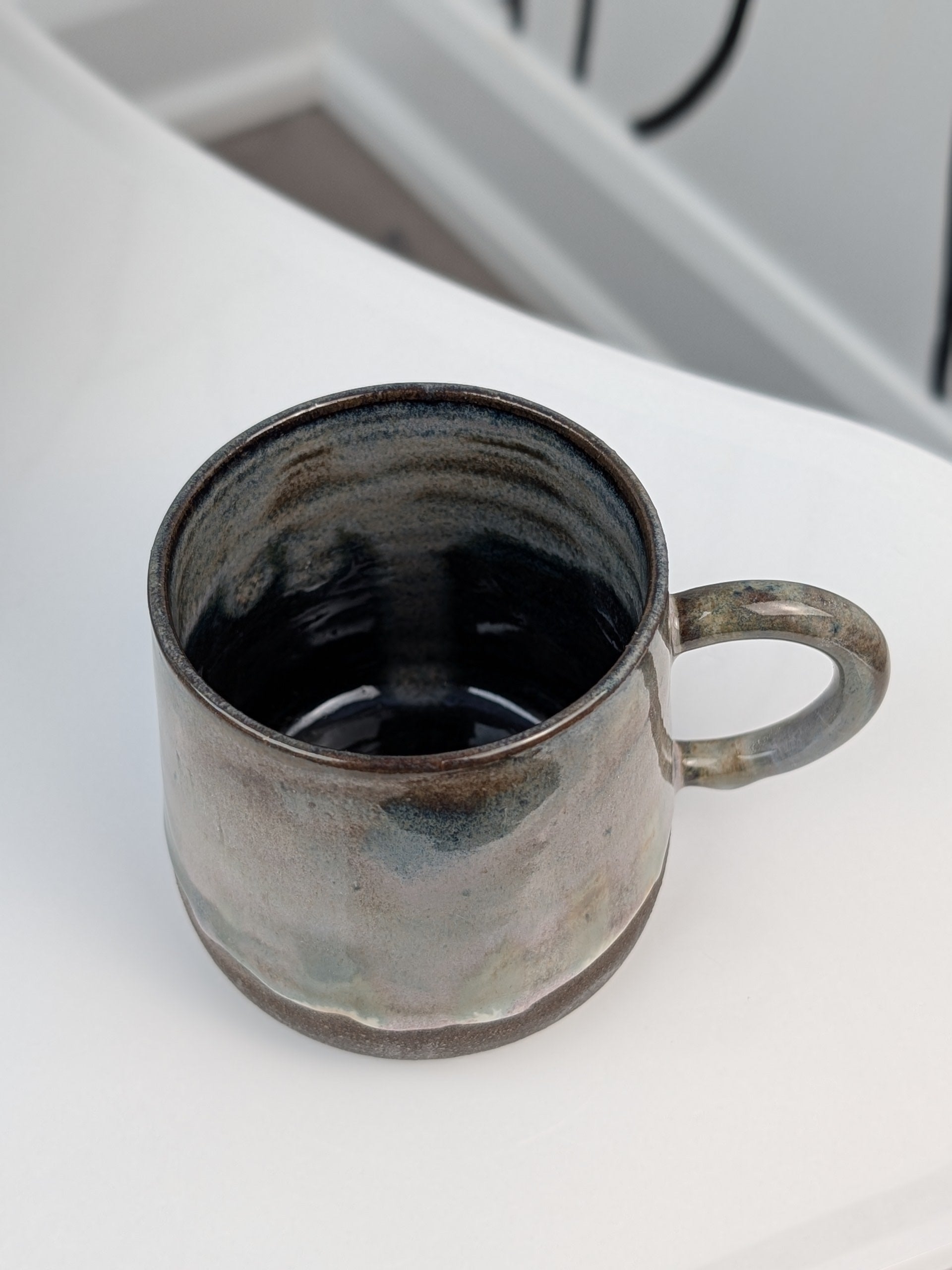 Handmade brown, green, and pink glazed ceramic cup, isometric view