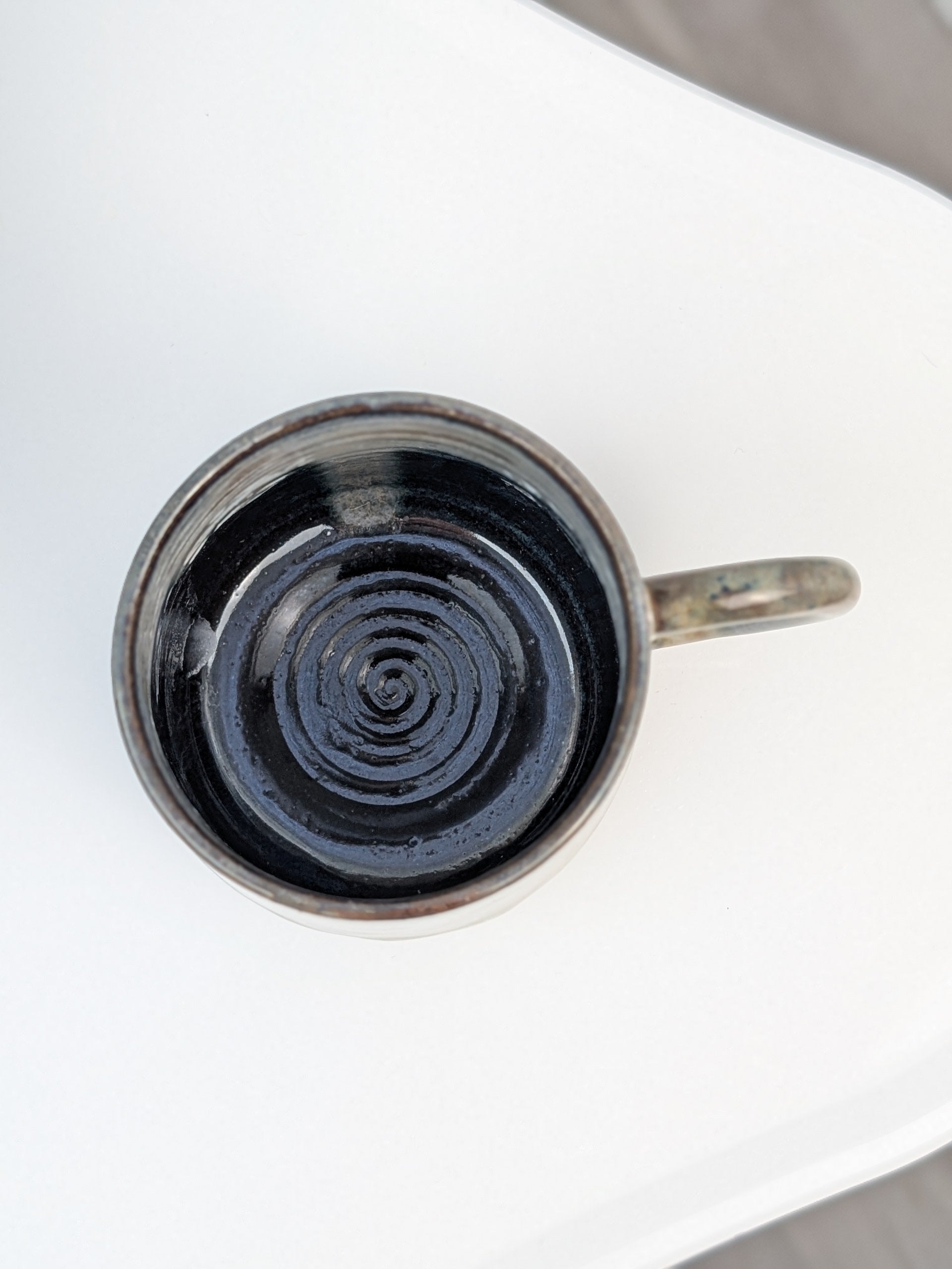 Handmade brown, green, and pink glazed ceramic cup, top view